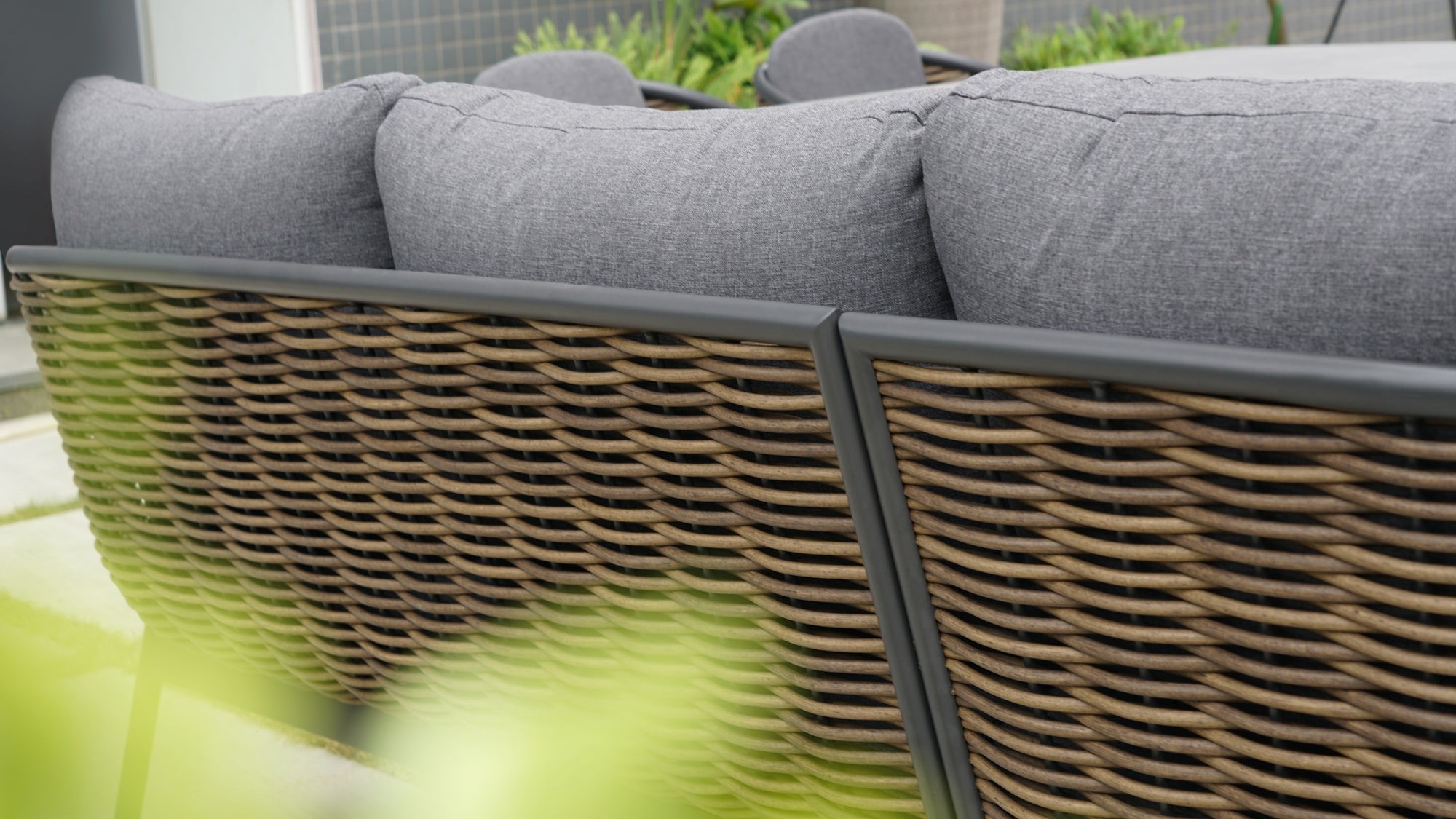 Die Garten Eckbankgruppe 'Claire' mit braun meliertem Kunststoffgeflecht, dunkelgrauen Kissen und einem Sinterstone-Tisch in Marmoroptik, angeboten von Gartenmöbelshop.at.